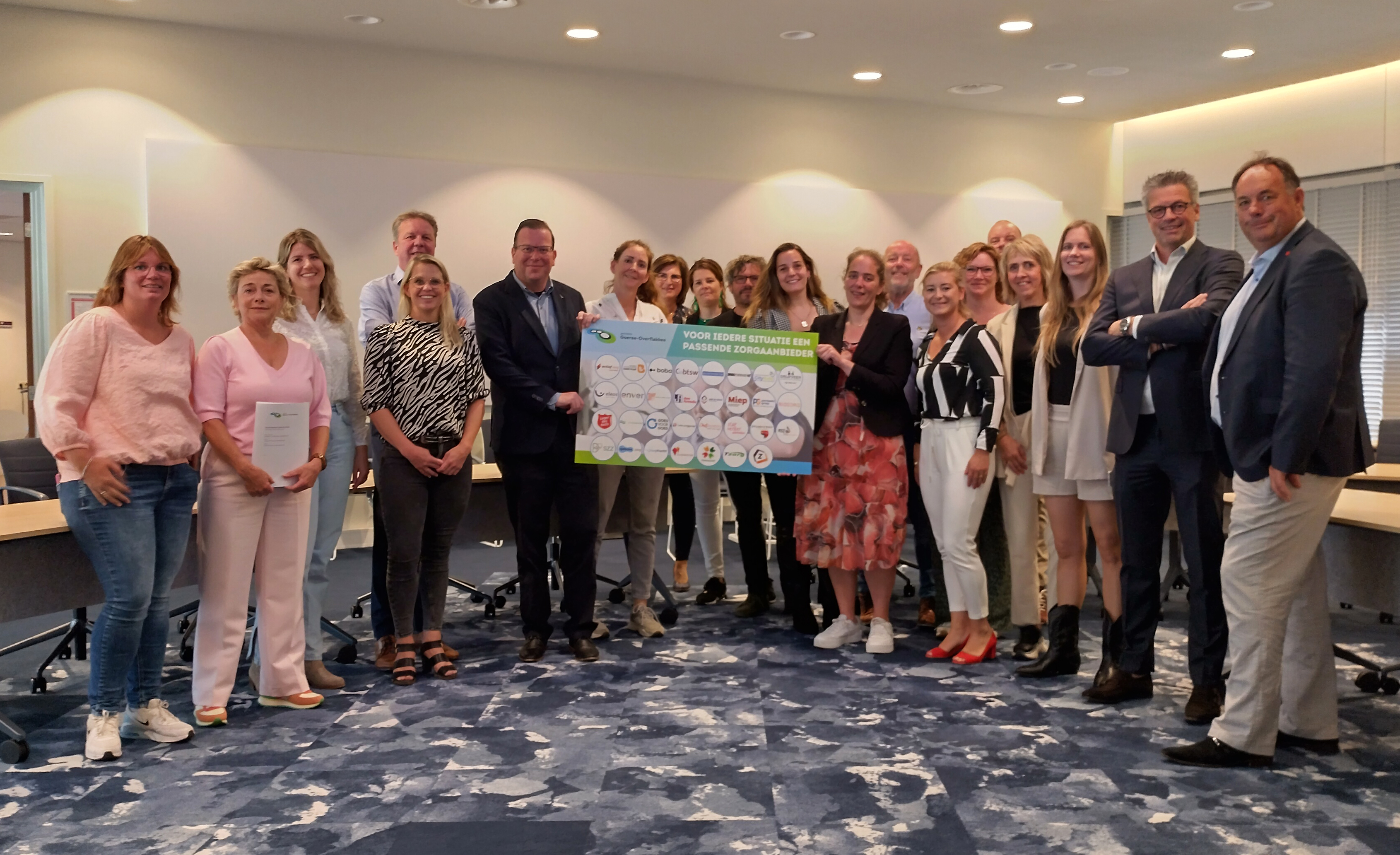 Wethouder Sociaal Domein en Welzijn Berend Jan Bruggeman en vertegenwoordigers van de zorgaanbieders tonen trots het bord met daarop de logo’s van de verschillende organisaties.